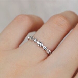 May include: A delicate silver band ring with a row of small, clear cubic zirconia stones set in a curved design.