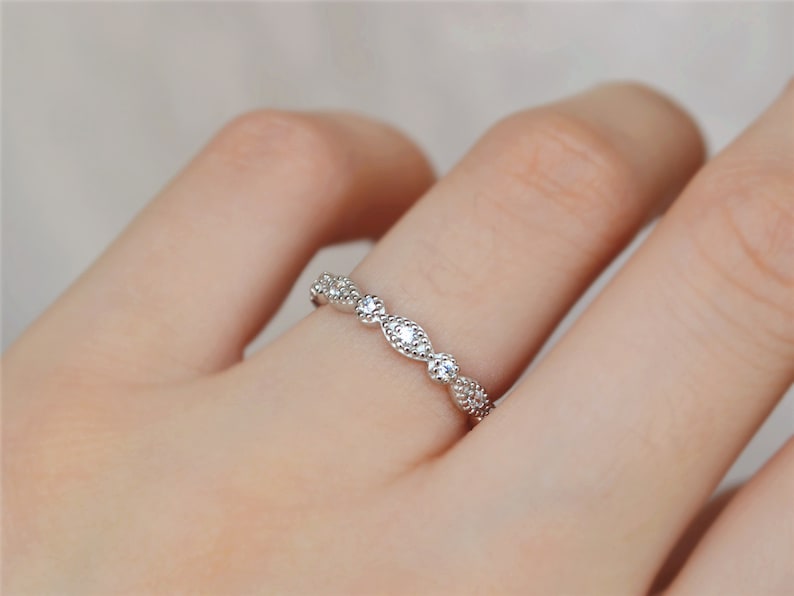 May include: A delicate silver band ring with a row of small, clear cubic zirconia stones set in a curved design.