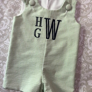 Peut inclure: Une grenouillère pour bébé rayée verte et blanche avec un monogramme brodé noir "H.G.W."