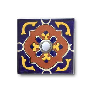 May include: A square ceramic doorbell button with a colorful, intricate tile design in shades of blue, yellow, orange, and white. The button is round and white, set within a silver frame.
