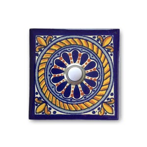 May include: A blue and yellow ceramic doorbell button with a white button in the center. The button has a floral design.