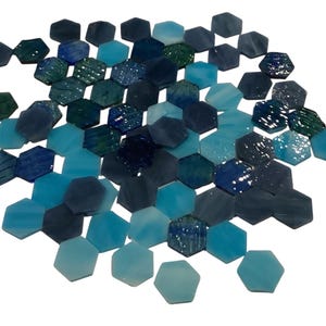 Könnte beinhalten: Eine Ansammlung sechseckiger Fliesen in verschiedenen Blau- und Grüntönen. Die Fliesen haben eine glänzende Oberfläche und sind in einem verstreuten Muster angeordnet. Die Farbpalette reicht von helltürkis bis tiefem Marineblau.