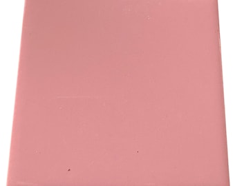 May include: A square, solid pink tile with a glossy finish. The tile is a soft, muted pink color and appears to be made of ceramic or a similar material. The edges are clean and well-defined, suggesting a high-quality product.
