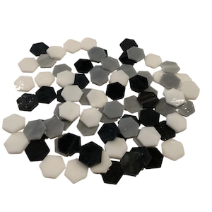 Puede incluir: Un conjunto de baldosas hexagonales en varios tonos de gris, negro y blanco. Las baldosas están dispuestas en un montón suelto, con un acabado brillante. Estas baldosas son adecuadas para proyectos de mosaicos o aplicaciones decorativas.
