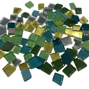 May include: A collection of small, square glass tiles in various shades of green, blue, silver, and gold. The tiles are scattered, showcasing their reflective surfaces and varying sizes. Ideal for mosaic art or craft projects.