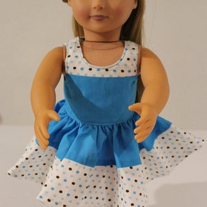 Puede incluir: Un vestido de lunares azules y blancos con un corpi&ntilde;o azul y una falda blanca. El vestido es sin mangas y tiene un escote redondo. La mu&ntilde;eca lleva el vestido y tiene el pelo rubio.