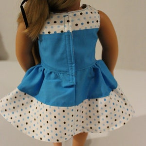 Puede incluir: Un vestido de lunares azules y blancos con un corpi&ntilde;o azul y una falda de lunares blancos y marrones. El vestido tiene una cremallera en la espalda.