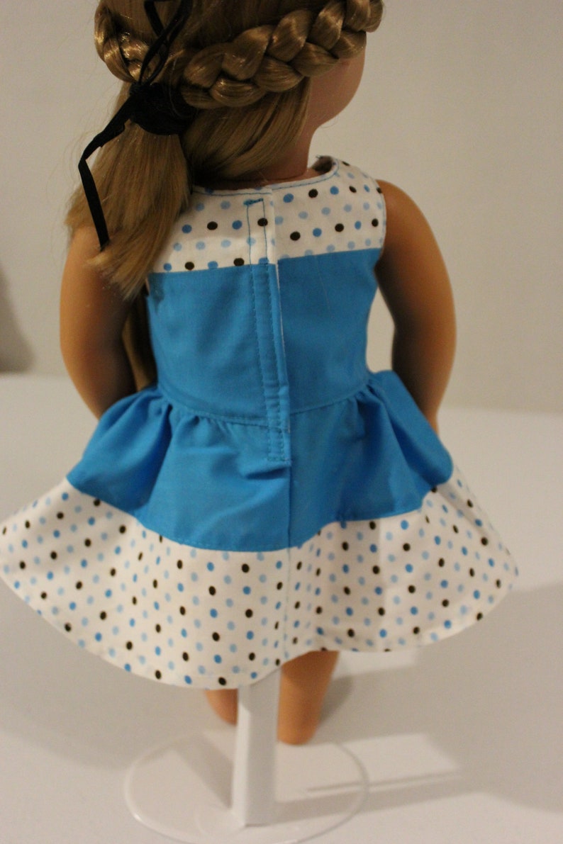 Puede incluir: Un vestido de lunares azules y blancos con un corpi&ntilde;o azul y una falda de lunares blancos y marrones. El vestido tiene una cremallera en la espalda.