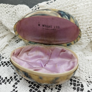 以下が含まれることがあります： ピンクのサテンの裏地が付いた、タートルの卵型のリングボックスが開いています。ボックスには「W. Wright Ltd. Jewellers.」と刻印されています。