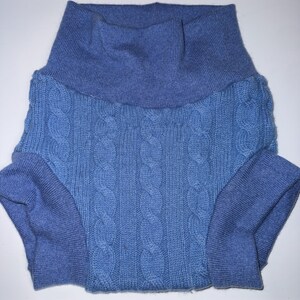 May include: A light blue knit garment featuring a high turtleneck collar and a central cable knit pattern. The piece has ribbed cuffs at the leg openings and a smooth, solid-coloured knit waistband, constructed from a soft, textured blue yarn.