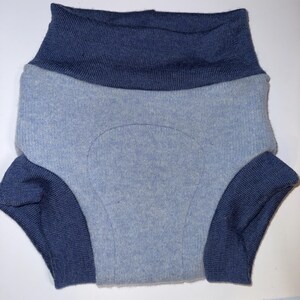 May include: A pair of knit underwear featuring a light blue main body with a textured, reinforced central panel. The garment includes a wide, dark blue ribbed waistband and matching dark blue ribbed leg cuffs, creating a two-tone colour scheme.