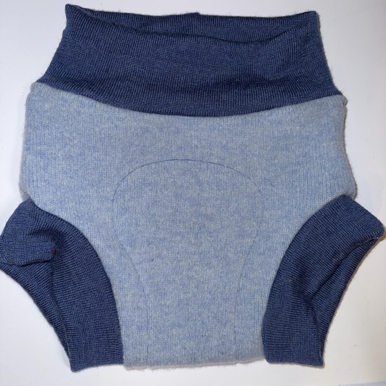 May include: A pair of knit underwear featuring a light blue main body with a textured, reinforced central panel. The garment includes a wide, dark blue ribbed waistband and matching dark blue ribbed leg cuffs, creating a two-tone colour scheme.