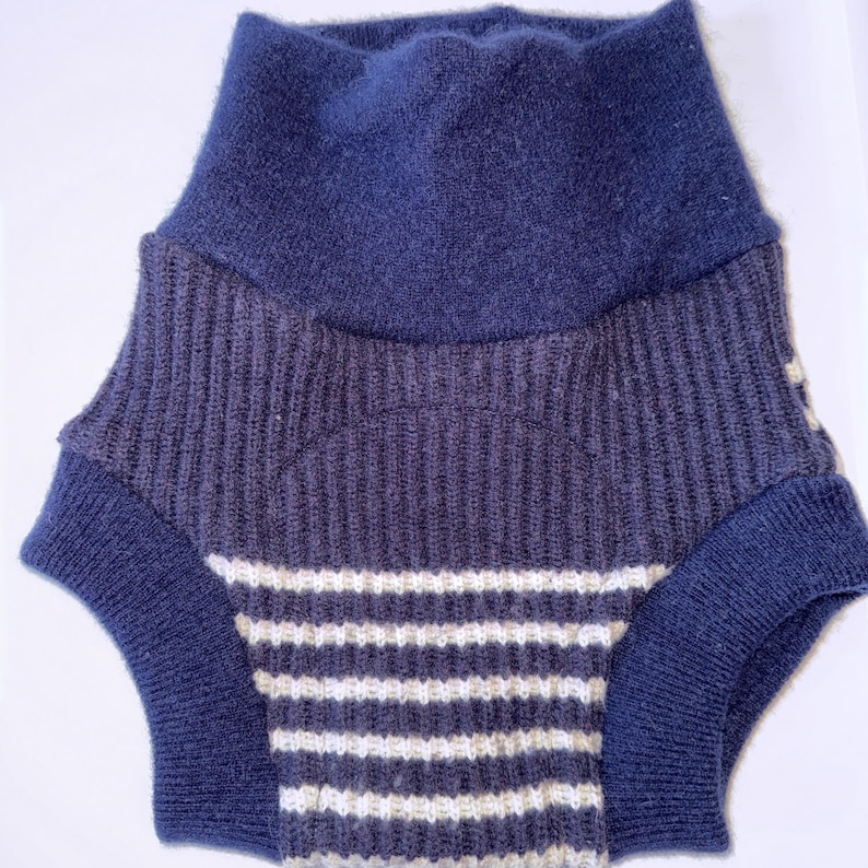 May include: A knitted garment featuring a high, solid navy blue waistband and a ribbed texture. The lower section displays a pattern of horizontal white and navy blue stripes, with solid navy blue ribbed leg openings for a secure fit.