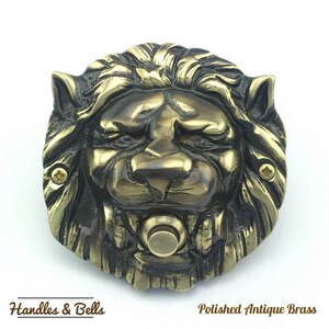 May include: A polished antique brass lion head door knocker with a round button in the center. The lion's mane is detailed and the knocker has a distressed finish.