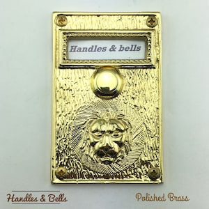 May include: A polished brass doorbell with a lion head design and a label that reads "Handles & bells".