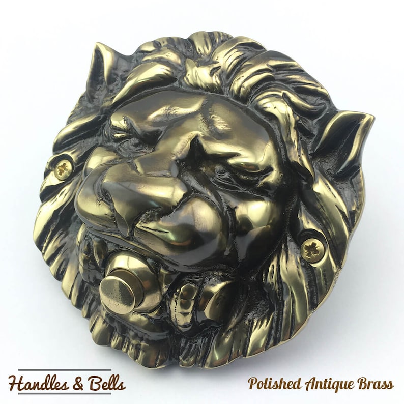 May include: A polished antique brass lion's head doorbell with a round button. The lion's head is detailed with a mane and a fierce expression. "Handles & Bells" and "Polished Antique Brass" are printed below the image.