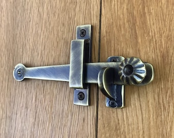 May include: A brass door latch with a decorative knob. The latch is attached to a wooden door.