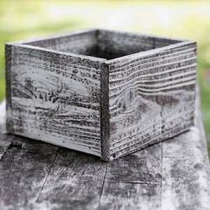 May include: A whitewashed wooden box with a rustic, weathered look. The box is empty and has a square shape.