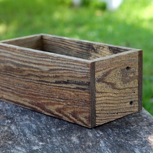 May include: A rustic wooden box with a natural wood finish. The box is empty and has a rectangular shape.