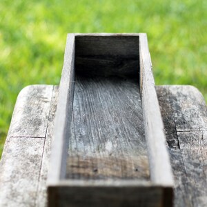 May include: A rustic wooden planter box with a weathered gray finish. The box is empty and ready to be filled with plants or flowers.