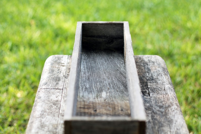 May include: A rustic wooden planter box with a weathered gray finish. The box is empty and ready to be filled with plants or flowers.