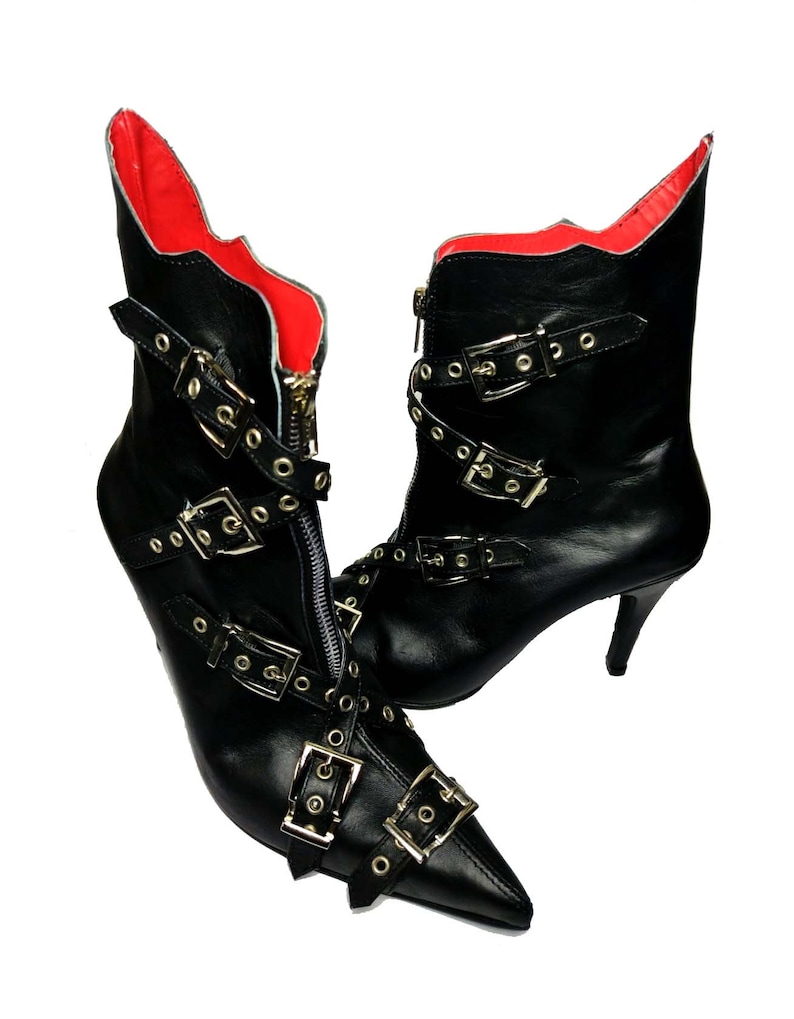 Puede incluir: Un par de botines de cuero negro con punta y tacones de aguja. Los botines presentan m&uacute;ltiples hebillas plateadas y cierre de cremallera. El forro interior es rojo.