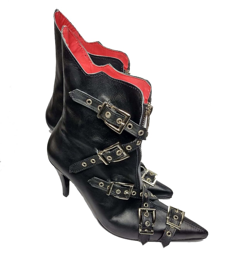 Puede incluir: Botines de cuero negro con puntera y m&uacute;ltiples hebillas plateadas. Las botas tienen cierre de cremallera y forro interior rojo. Los tacones son de estilo stiletto.