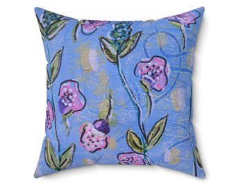 Puede incluir: Cojín cuadrado con un diseño floral. El cojín presenta un fondo azul claro con diseños florales rosas, morados y verdes. Las flores tienen un aspecto pintado, agregando un toque artístico al cojín decorativo.