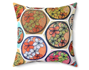 Könnte beinhalten: Quadratisches Zierkissen mit einem farbenfrohen Blumenmuster. Das Design zeigt Blumen in Orange, Rot, Gelb und Grün, angeordnet in kreisförmigen und sechseckigen Formen auf weißem Hintergrund. Das Kissen hat ein weiches, strukturiertes Aussehen.