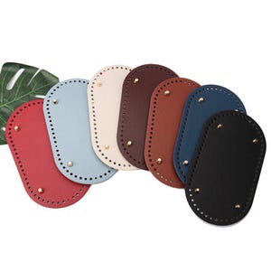 May include: A collection of seven oval-shaped bag bases in red, light blue, cream, dark brown, medium brown, navy blue, and black. Each base features a series of pre-punched holes along the perimeter and four small gold-toned metal feet.