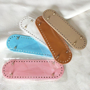 May include: Four oval-shaped bag bases in pink, light blue, white, and tan, each featuring a series of pre-punched holes along the perimeter and four small metal feet attached to the underside, all individually wrapped in clear plastic packaging.