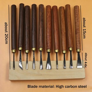Op de afbeelding: Een set houtsnijgereedschappen met donkerbruine houten handvatten en metalen messen. De handvatten zijn ongeveer 20 cm lang en de messen ongeveer 4-6 cm. De gereedschappen worden gepresenteerd op een lichtbruin houten blok. Materiaal lemmet: hoog koolstofstaal.