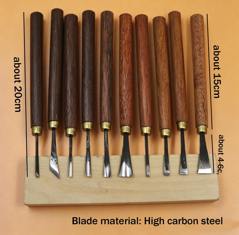 Op de afbeelding: Een set houtsnijgereedschappen met donkerbruine houten handvatten en metalen messen. De handvatten zijn ongeveer 20 cm lang en de messen ongeveer 4-6 cm. De gereedschappen worden gepresenteerd op een lichtbruin houten blok. Materiaal lemmet: hoog koolstofstaal.