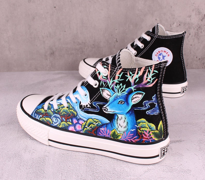 May include: Black high-top canvas sneakers with a hand-painted design featuring a blue deer, green foliage, and a flowing stream. The sneakers have white soles and black laces. The brand name "DABOWEN" is printed on the side of the shoe.