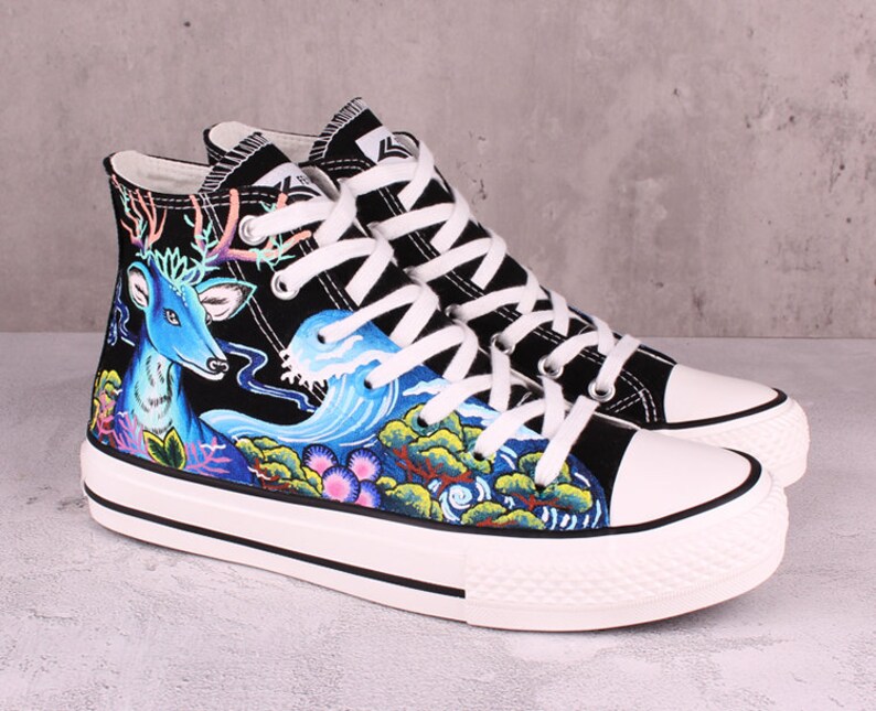 May include: Black high-top canvas sneakers with a hand-painted design featuring a blue deer, waves, and flowers.