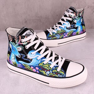 May include: Black high-top canvas sneakers with a white sole. The sneakers feature a colorful design of a deer, waves, and trees.