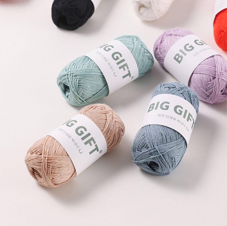 May include: Several skeins of yarn in various pastel colors including light blue, lavender, beige, and mint green. Each skein is wrapped in a white paper band featuring the text BIG GIFT in bold black letters along with smaller Korean characters.