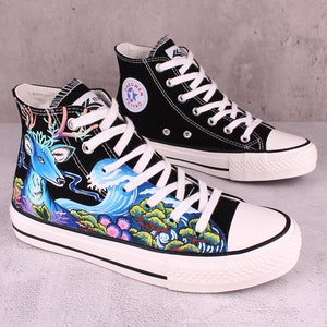 May include: Black high-top canvas sneakers with a blue deer and wave design. The sneakers have white laces and a white sole.
