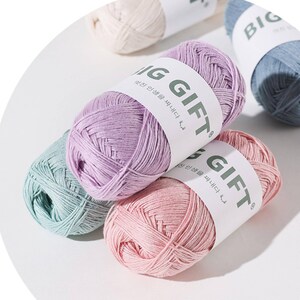 May include: Several skeins of yarn in pastel shades of lavender, pink, mint green, cream, and blue. Each skein is wrapped in a white paper band featuring the text BIG GIFT in bold dark green letters, along with smaller Korean script text.