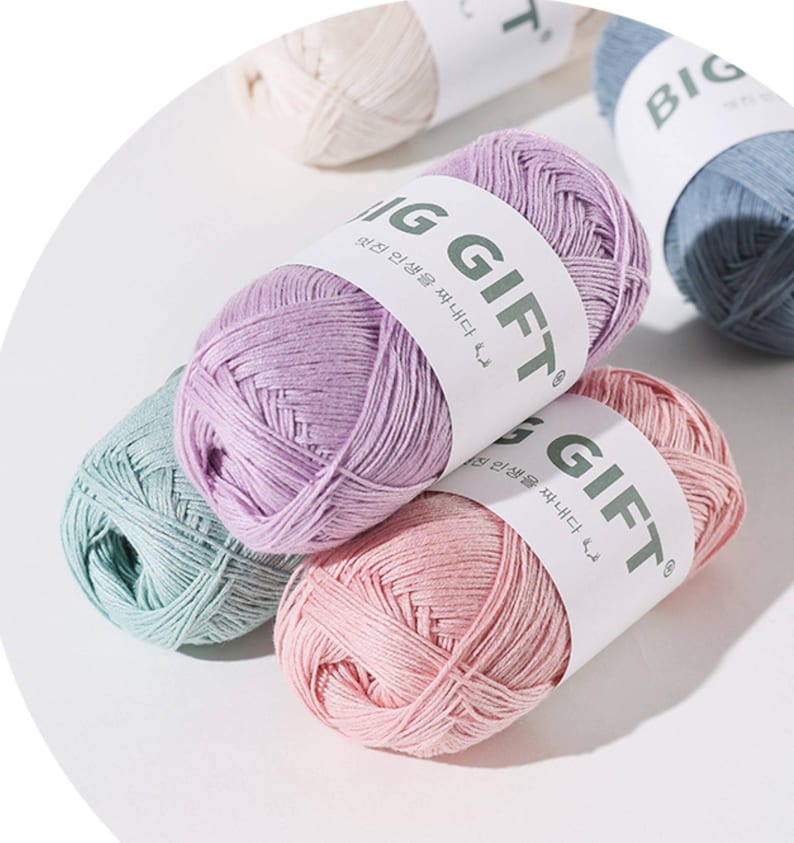 May include: Several skeins of yarn in pastel shades of lavender, pink, mint green, cream, and blue. Each skein is wrapped in a white paper band featuring the text BIG GIFT in bold dark green letters, along with smaller Korean script text.
