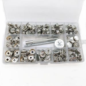 May include: A clear plastic storage container filled with various silver-colored metal snap fasteners, screws, and two metal installation tools. The kit includes multiple compartments organizing the different components of the fastener sets.