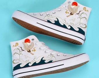 May include: White high-top canvas sneakers with a red sun, gold crane, and blue waves design.