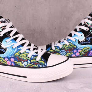 May include: A pair of black high-top canvas shoes with a colorful hand-painted design featuring a blue deer, waves, and trees.
