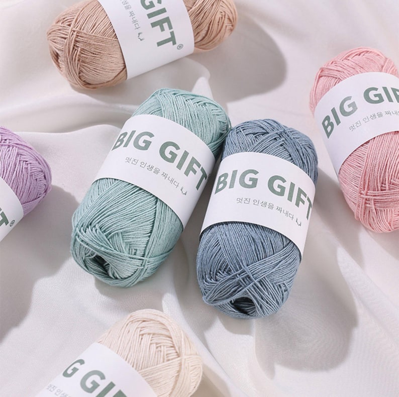 May include: Multiple skeins of yarn in various pastel colors including light blue, sage green, soft pink, lavender, and beige. Each skein is wrapped in a white paper band featuring the text BIG GIFT in bold black letters with Korean script.