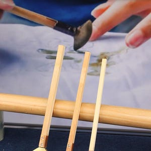 May include: Three wax knives with wooden handles and brass-coloured blades. The text "Half circle wax knife" is at the top. The blade sizes are 3.8cm, 3cm, and 2.2cm. The knives are for thicker lines or large-area waxing.