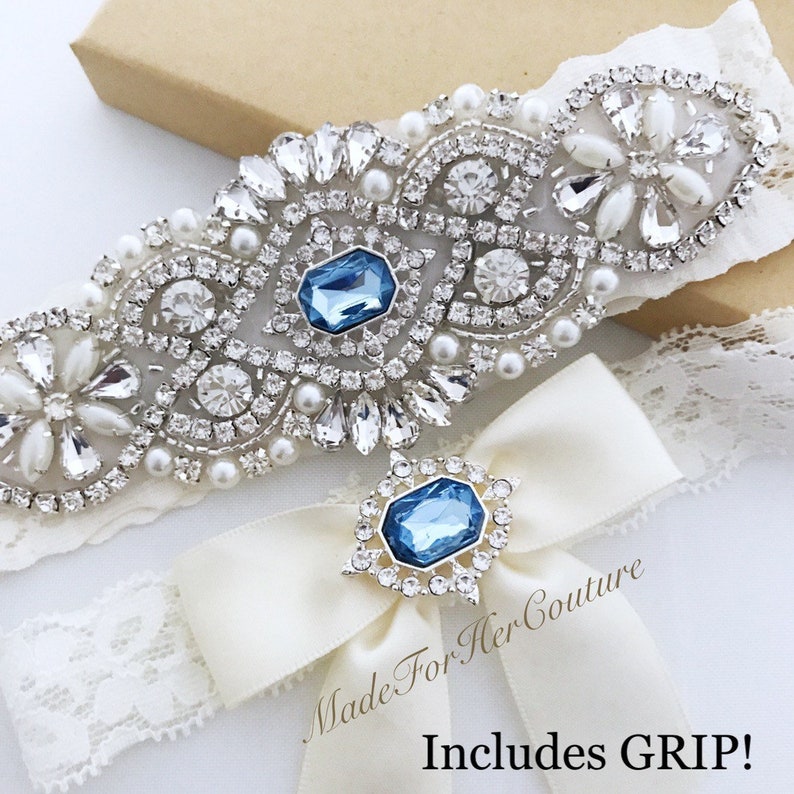 Rhinestone and pearls applique on ivory lace accented with a light blue stone in the center for the keepsake garter. Toss garter has a 3-inch-wide bow with a light blue stone surrounded with small rhinestones.