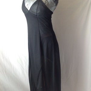 May include: A black halter dress with a V-neckline and a flowing, asymmetrical skirt. The dress is made of a sheer fabric, and the bodice has a solid panel. The dress is displayed on a mannequin.