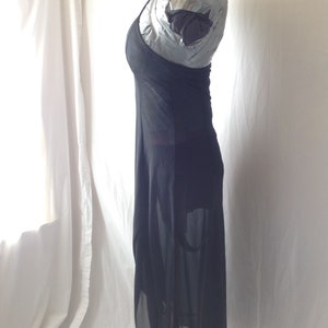 May include: A black, floor-length dress with a halter neckline. The dress is made of a sheer fabric, with a flowing skirt and a fitted bodice. The dress is displayed on a mannequin against a white background.