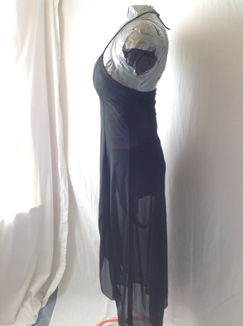 May include: A black, floor-length dress with a halter neckline. The dress is made of a sheer fabric, with a flowing skirt and a fitted bodice. The dress is displayed on a mannequin against a white background.
