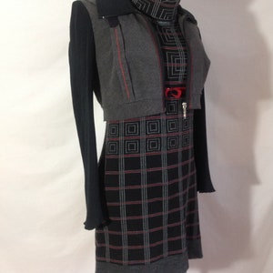 May include: A gray and black dress with a plaid pattern, paired with a matching gray bolero jacket and a black long-sleeved top. The dress features a high neckline and a red accent at the waist. The jacket has red stitching.